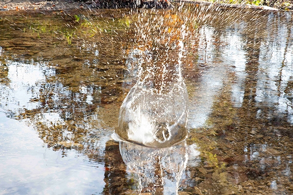 Foto eines Sees, die Wasseroberfläche ist bewegt von einem Gegenstand der hineingefallen
                                          ist.