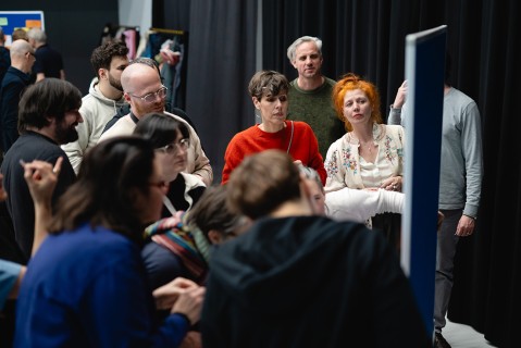 A group of people is standing around a poster at a workshop