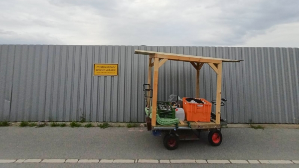 Ein Holzwagen vor einem metallenen Baustellenzaun