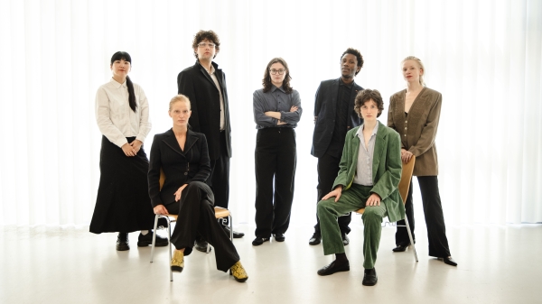 Eine Gruppe von 7 Personen
                                          steht vor einem hellen weißen Hintergrund und posiert für die Kamera. 